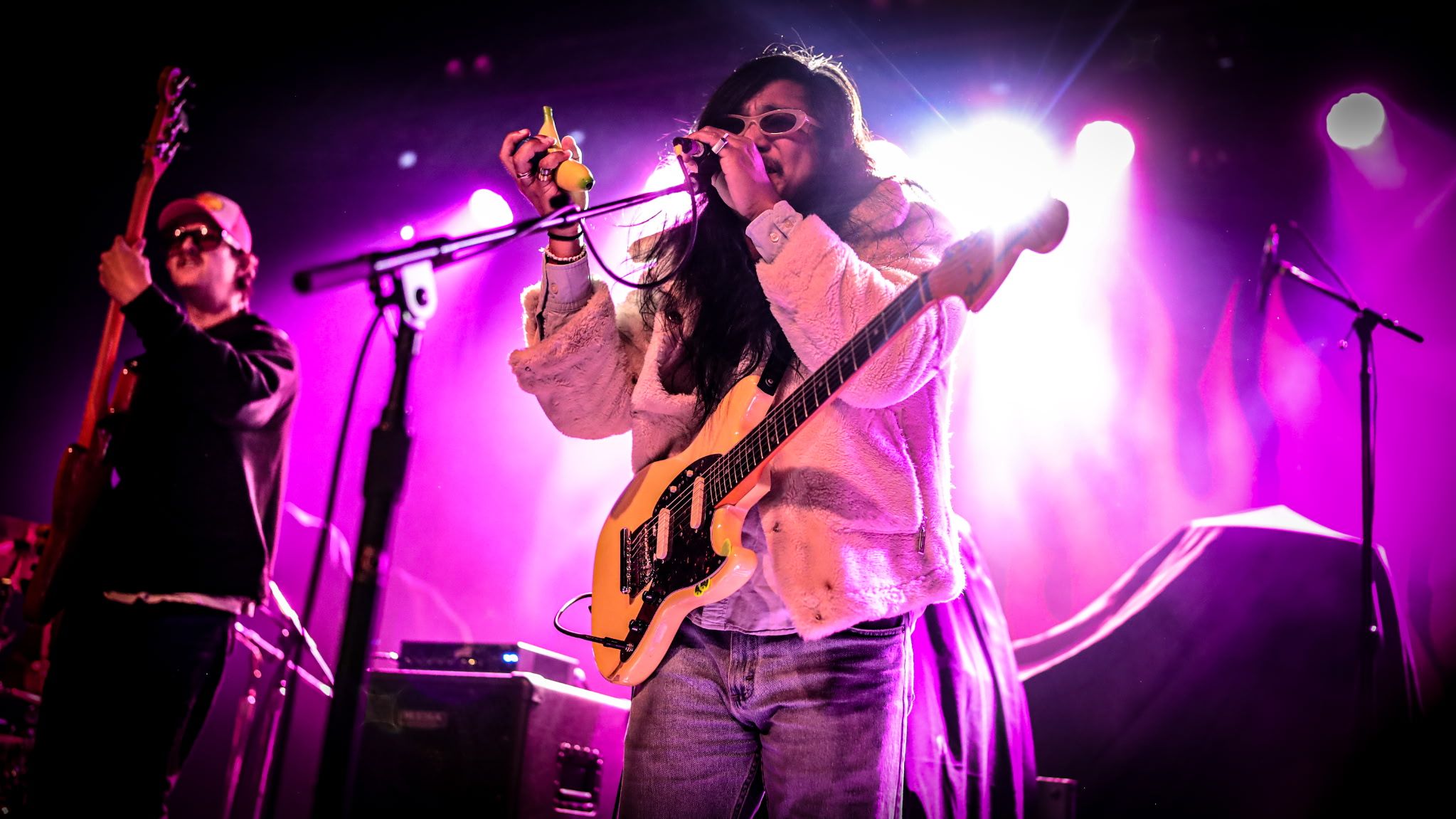 Moon Dough on stage under magenta light, singing with a guitar